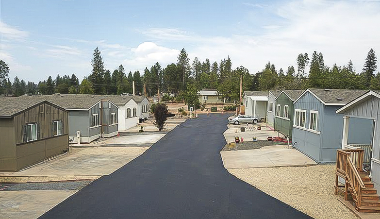 Paradise Estates manufactured home community: homes lining a main street in the community with blue skies and green trees on the horizon